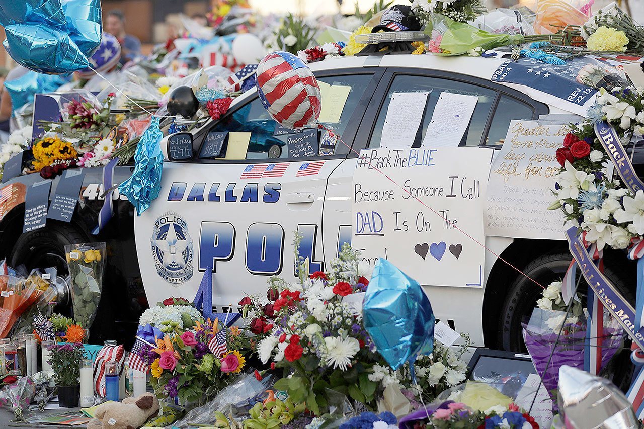 Notes, flowers and other items decorate a squad car at a make-shift memorial in front of the Dallas police department Saturday. (AP Photo/Eric Gay)