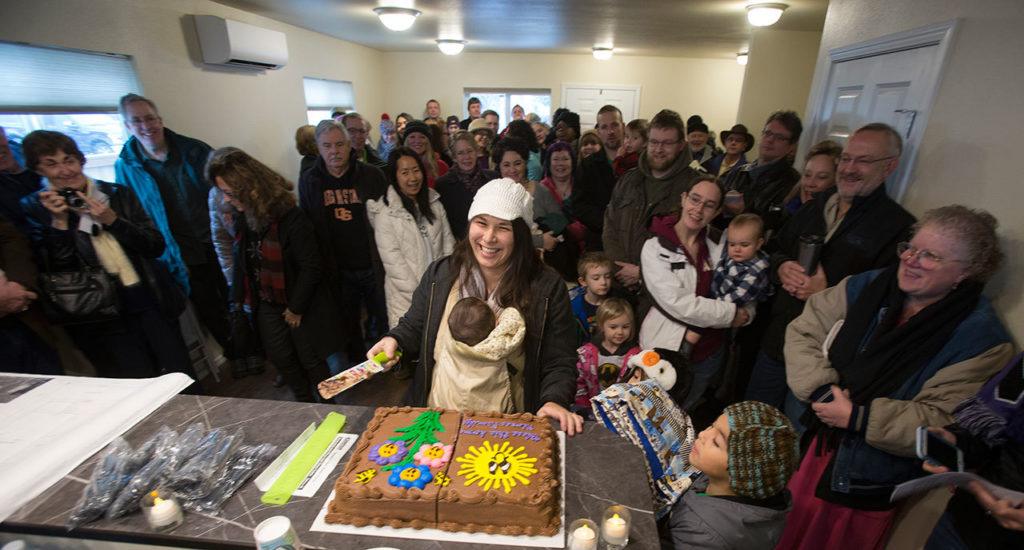 Sandy Flores cuts a cake for dozens of guests after accepting the keys to their new home from Habitat for Humanity of Snohomish County on Saturday in Everett. (Andy Bronson / The Herald)
