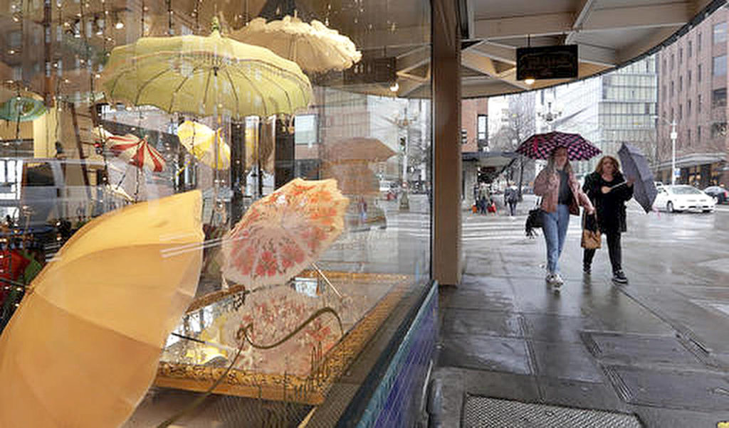 In This Jan. 18 photo, pedestrians under umbrellas pass a vintage umbrella shop in downtown Seattle. (AP Photo/Elaine Thompson,File)
