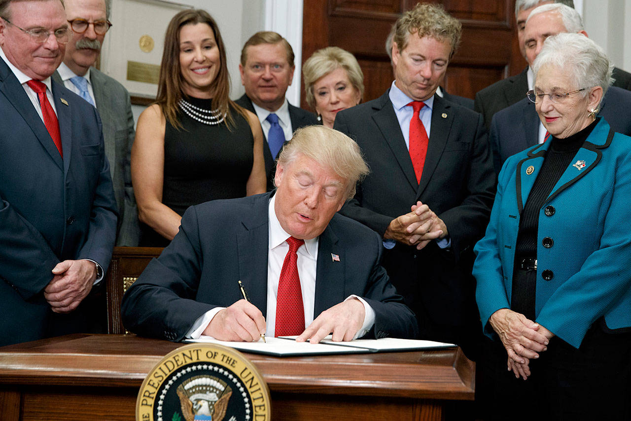 President Donald Trump signs an executive order on health care in the Roosevelt Room of the White House on Thursday in Washington. (AP Photo/Evan Vucci)