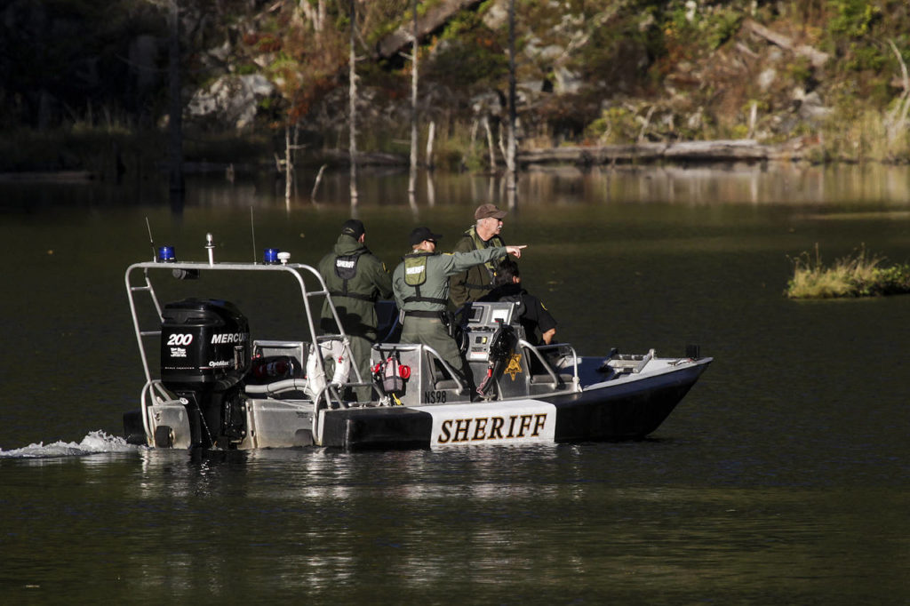 Investigators make their way across King Lake near the site of a helicopter crash Tuesday. (Ian Terry / The Herald)
