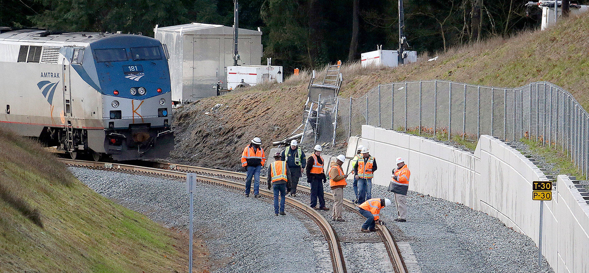 Workers look over tracks near the rear engine of a crashed Amtrak train on Tuesday in DuPont. The train that careened off an I-5 overpass on Monday. (AP Photo/Elaine Thompson)