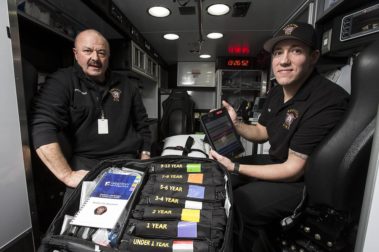 Capt. Dan Harbeck (left) and firefighter Eric Shaeffer of the Mukilteo Fire Department hold a new Handtevy kit which utilizes an iPad application to help calculate accurate medicine dosages for children. (Andy Bronson / The Herald)