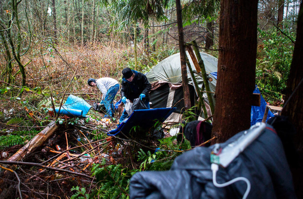 Michael Jensen (left) and Nathan Jensen pick up trash in their encampment near Silver Lake in Everett on Wednesday. They are being forced to clear out by city’s Parks Department. (Olivia Vanni / The Herald)
