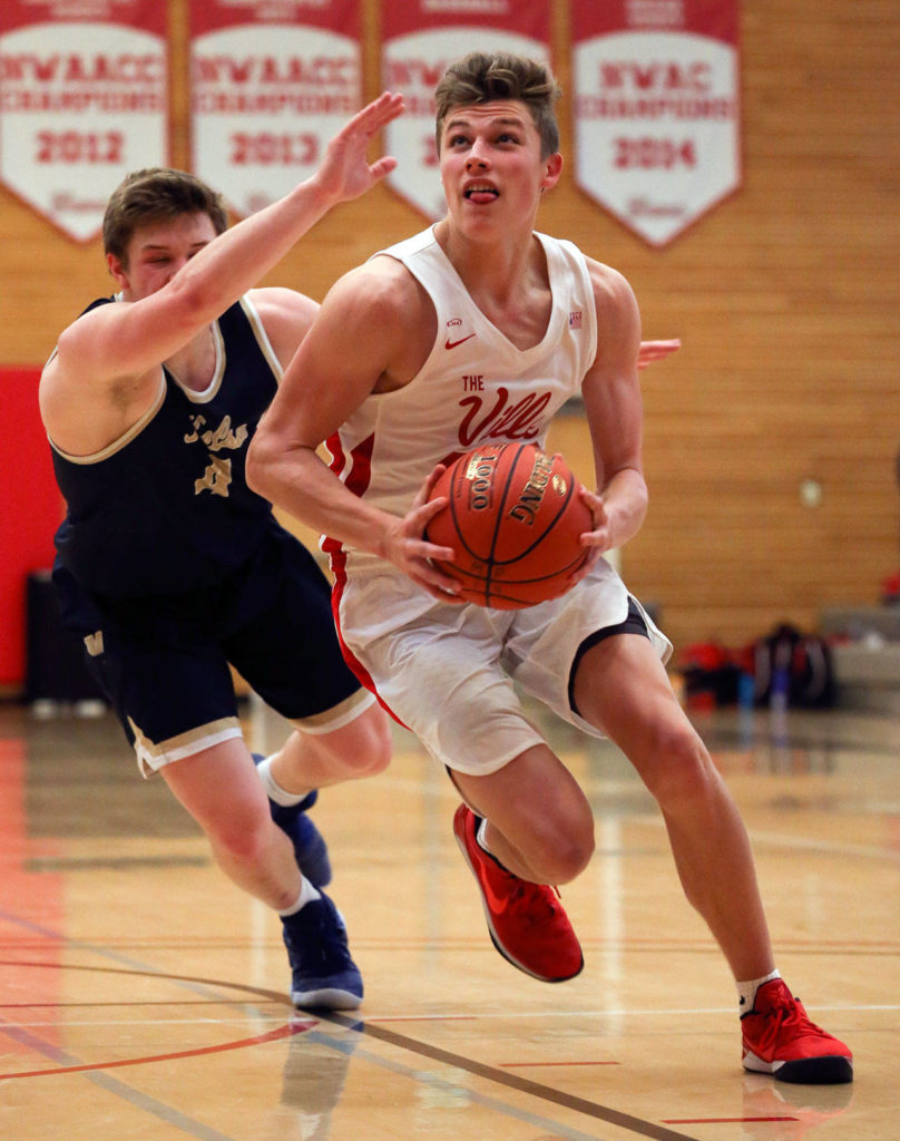 Marysville Pilchuck’s Aaron Kalab drives to the basket with Kelso’s Riley Noah trailing during a 3A state regional game on Feb. 22 at the Walt Price Student Fitness Center on the campus of Everett Community College. (Kevin Clark / The Herald)
