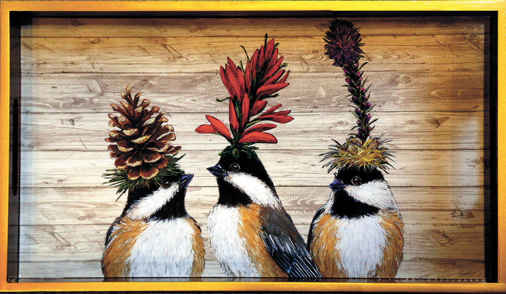 A lacquered wooden tray is painted with birds wearing plumes made of pine cones and wild flowers. (Dan Bates / The Herald)
