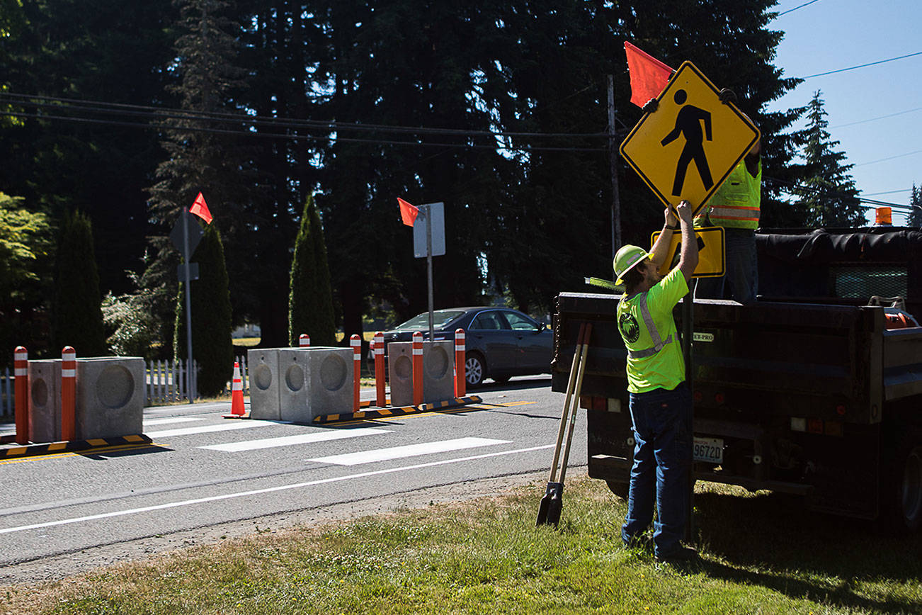 Arlington Public Works staff install the final crosswalk sign at the completed cross walk at the corner of 180th Street NE and Smokey Point Boulevard on Sunday, June 27, 2021 in Arlington, Wa. (Olivia Vanni / The Herald)