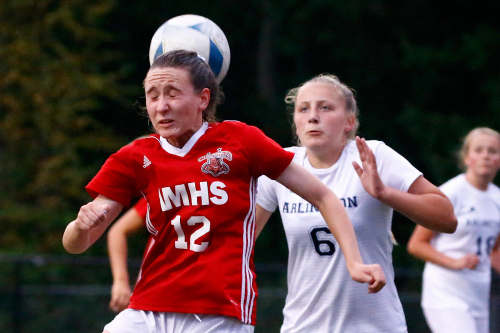 Archbishop Murphy’s Lilia Echols, left, misses the header with Arlington’s Madyson Williams trailing at Archbishop Murphy High School Tuesday night in Everett on September 14, 2021. The Wildcats won 6-1. (Kevin Clark / The Herald)
