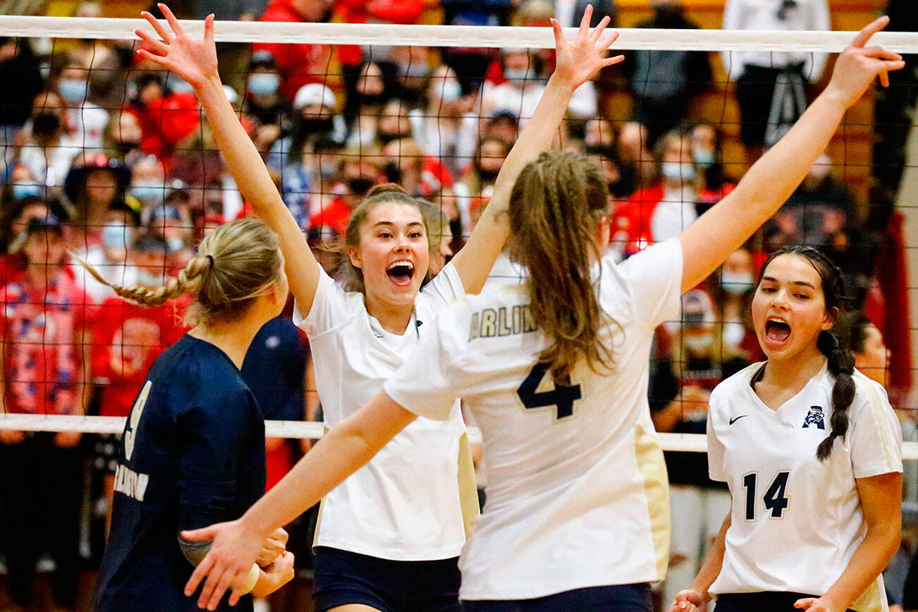 Arlington's Chloe Lewis, left to right, Emily Mekelburg, Malia Shepherd and Chloe Fochesato celebrate a point against Stanwood Thursday evening during the 3A District volleyball playoffs at Marysville-Pilchuck High School on November 11, 2021.            
(Kevin Clark / The Herald)