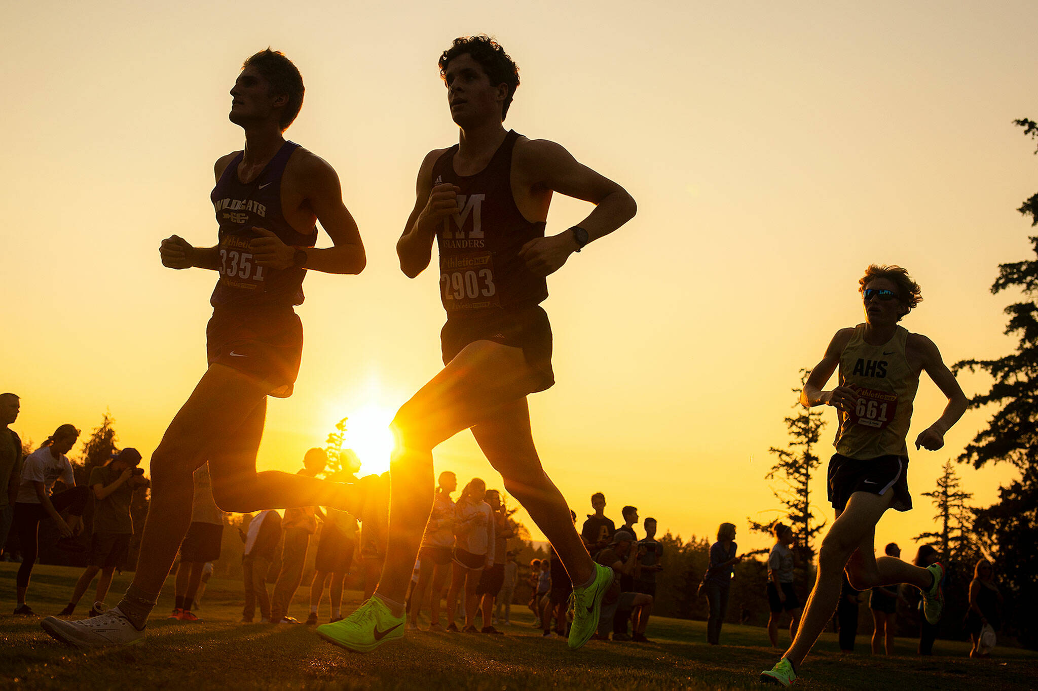 Runners in the 3A-4A Boys 5K turn a corner as the sun sets during the Nike Twilight Cross Country Invitational on Saturday, Oct. 1, 2022, at Cedarcrest Golf Course in Marysville, Washington. (Ryan Berry / The Herald)