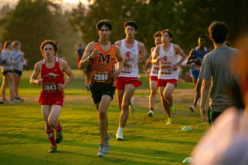 Runners pass the halfway point in the Boys 3A-4A 5K during the Nike Twilight Cross Country Invitational on Saturday, Oct. 1, 2022, at Cedarcrest Golf Course in Marysville, Washington. (Ryan Berry / The Herald)

