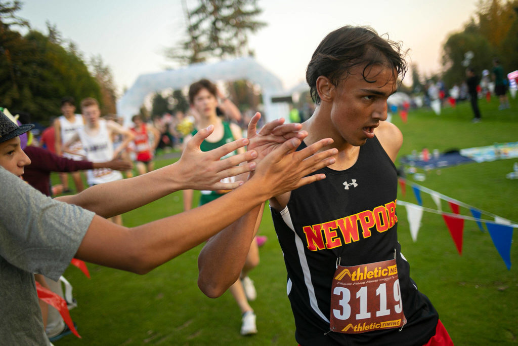 Runners receive high fives at the end of the 3A-4A Boys 5K during the Nike Twilight Cross Country Invitational on Saturday, Oct. 1, 2022, at Cedarcrest Golf Course in Marysville, Washington. (Ryan Berry / The Herald)

