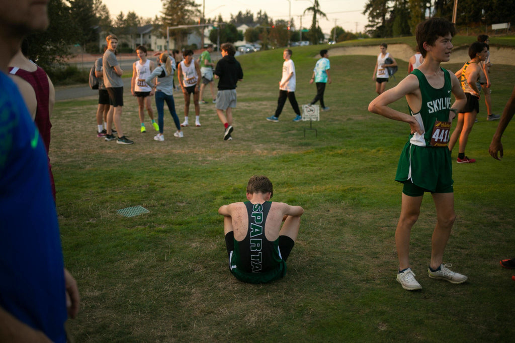 A runner takes a moment after finishing the Boys 3A-4A 5K during the Nike Twilight Cross Country Invitational on Saturday, Oct. 1, 2022, at Cedarcrest Golf Course in Marysville, Washington. (Ryan Berry / The Herald)

