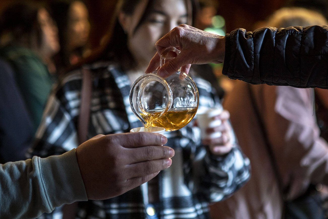 Joan Chissus, right, pours attendees oolong tea during the Cascadia Tea spring festival at Floral Hall in Everett, Washington on Saturday, April 15, 2023. (Annie Barker / The Herald)