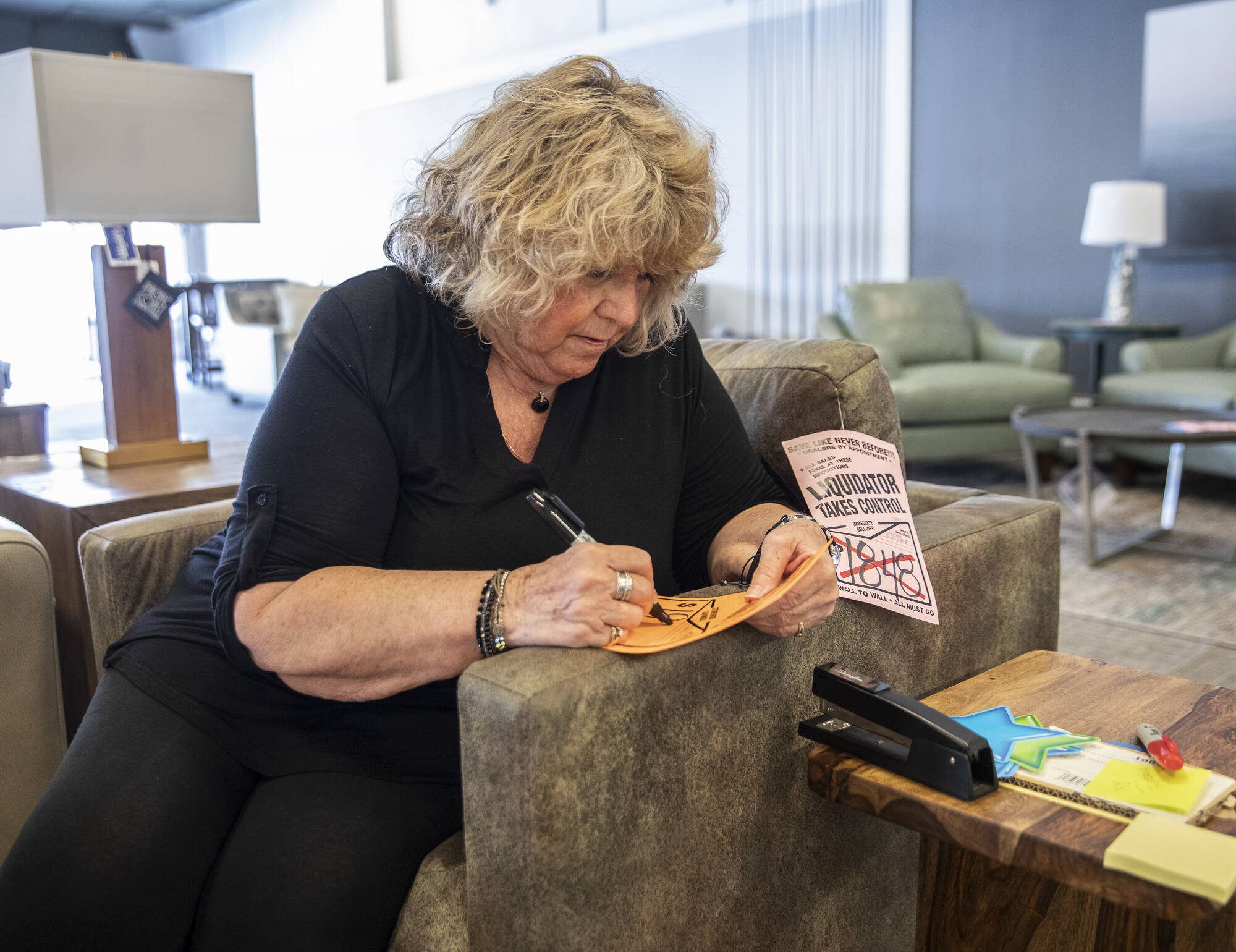 Kathy Tiger writes new prices for furniture after Behars was purchased by Conlins on Thursday, Aug. 24, 2023 in Everett, Washington. (Olivia Vanni / The Herald)