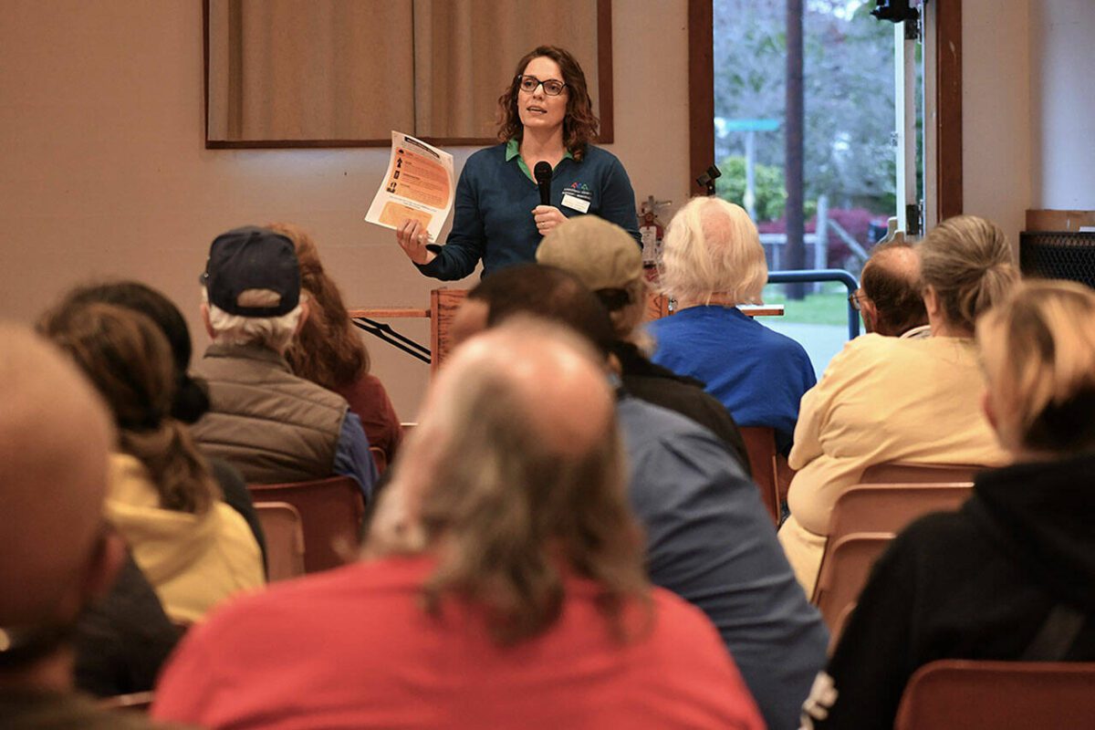 The Snohomish County Emergency Management Director Lucia Schmit speaking during a community meeting with a packet of information in her hand