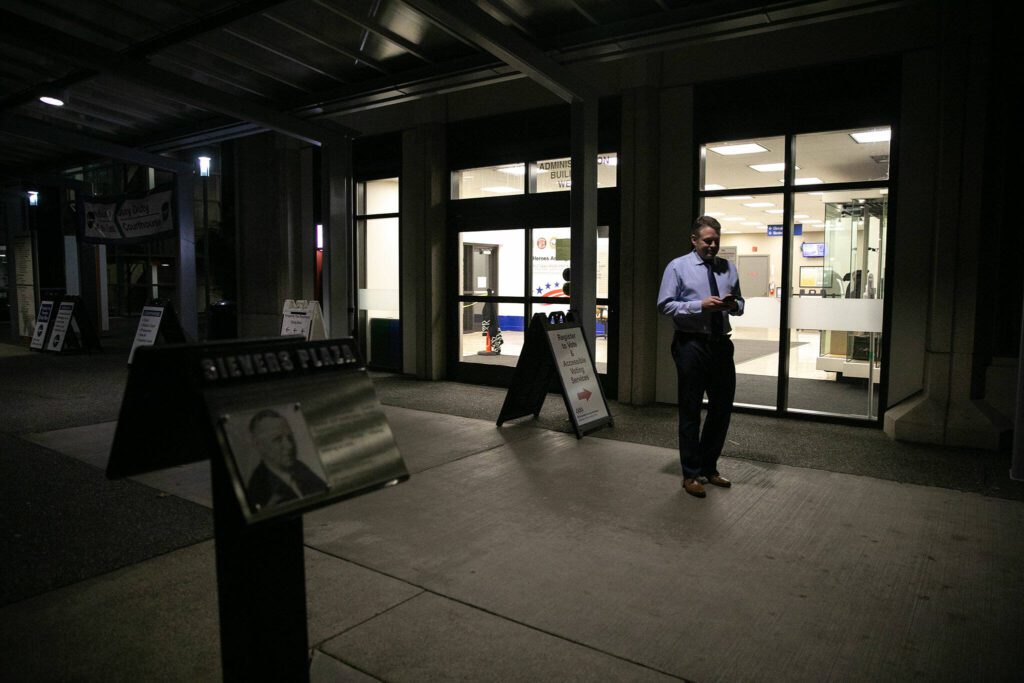 Garth Fell, incumbent Snohomish County Auditor, steps outside and away from his work in the elections office to text family about the initial results of his race to continue as auditor on Tuesday, Nov. 7, 2023, in downtown Everett, Washington. (Ryan Berry / The Herald)
