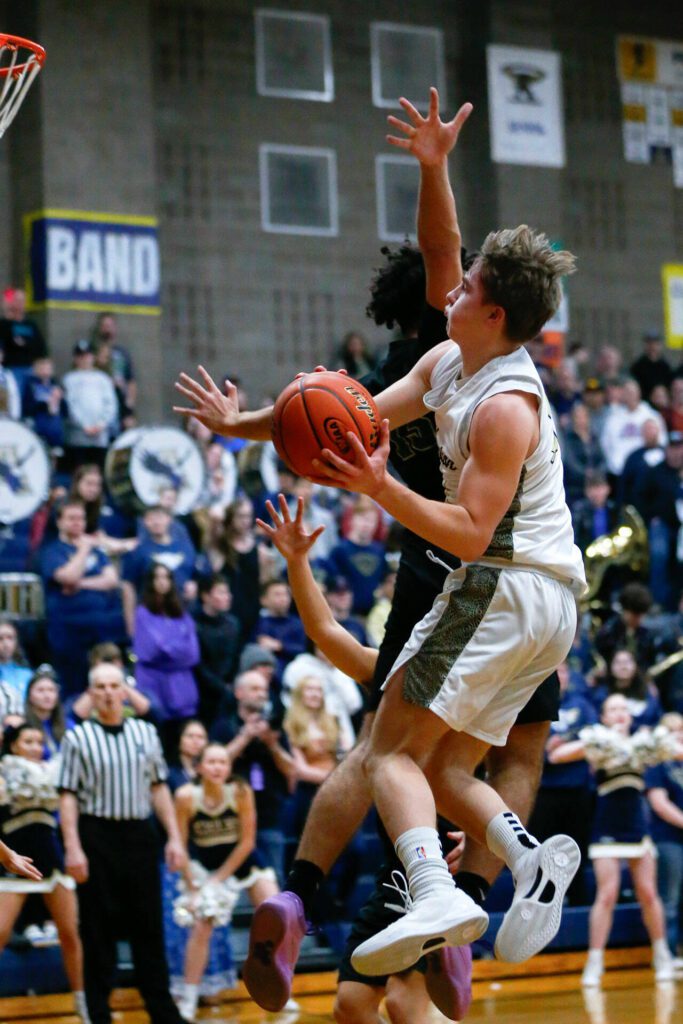 Arlington’s Leyton Martin weaves midair to score against Marysville Getchell during a playoff matchup at Arlington High School on Saturday, Feb. 24, 2024, in Arlington, Washington. (Ryan Berry / The Herald)
