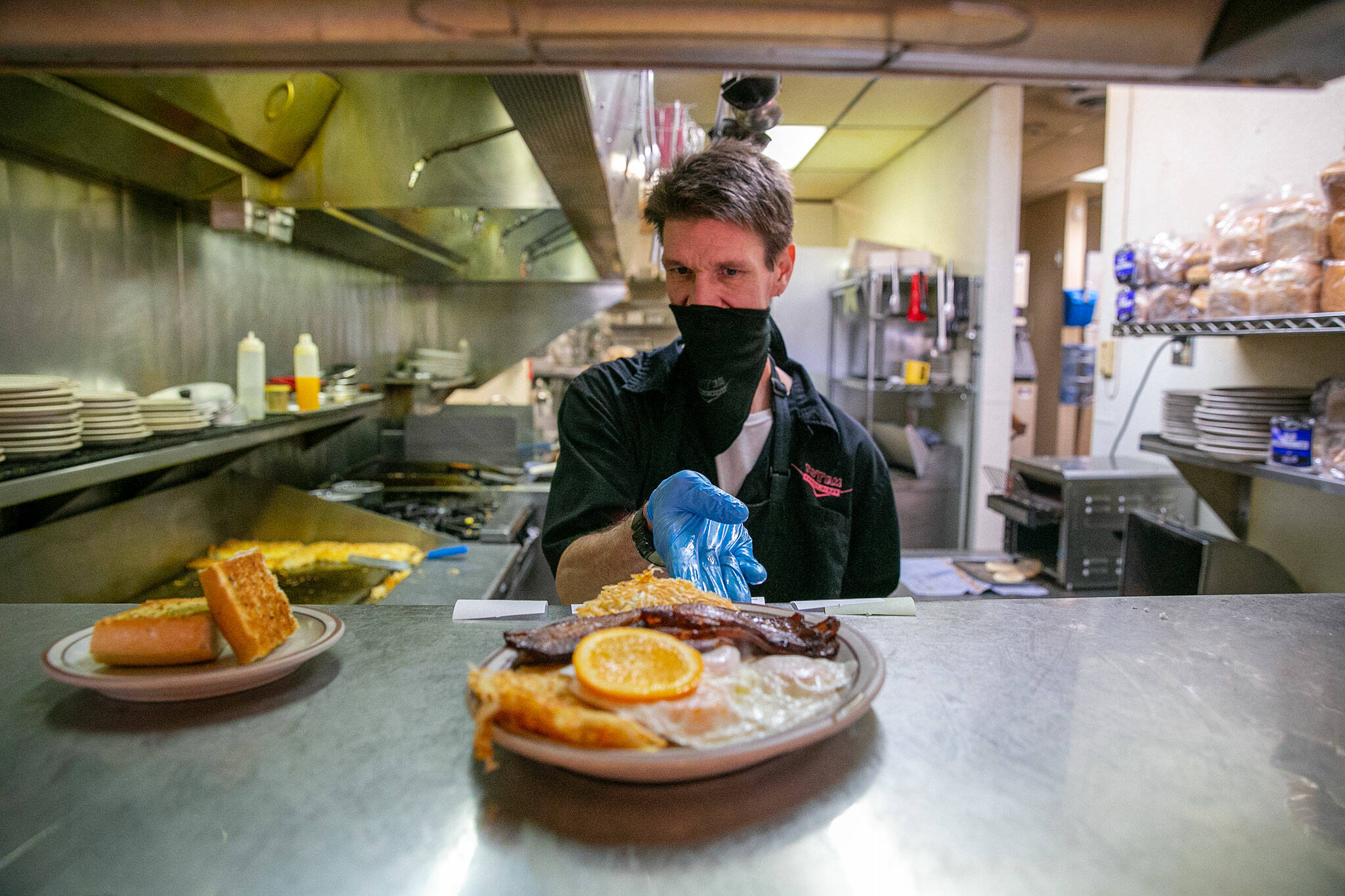 Lead cook Wes Bazin, who has worked at Totem Family Diner on-and-off for more than a decade, puts a #13 up in the window during lunch service on Saturday, Jan. 14, 2023, in Everett, Washington. Totem is one of countless restaurants nationwide feeling the pressure from increased prices and a lower supply of eggs. (Ryan Berry / The Herald)