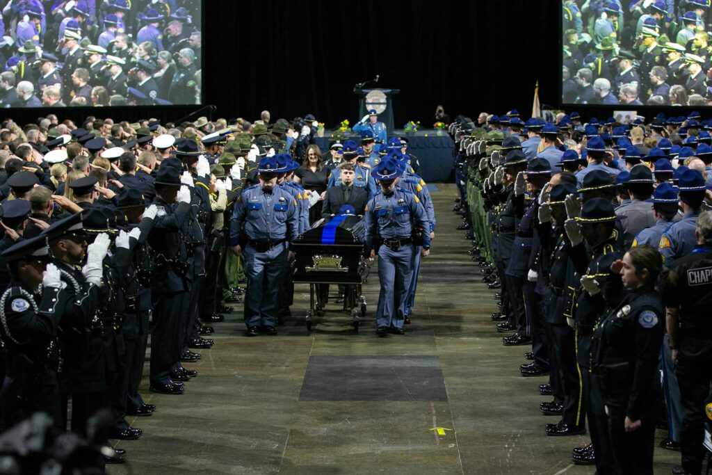 Washington State Patrol trooper Chris Gadd’s casket is brought out by fellow troopers following a memorial ceremony on Tuesday, March 12, 2024, at Angel of the Winds Arena in Everett, Washington. (Ryan Berry / The Herald) 
