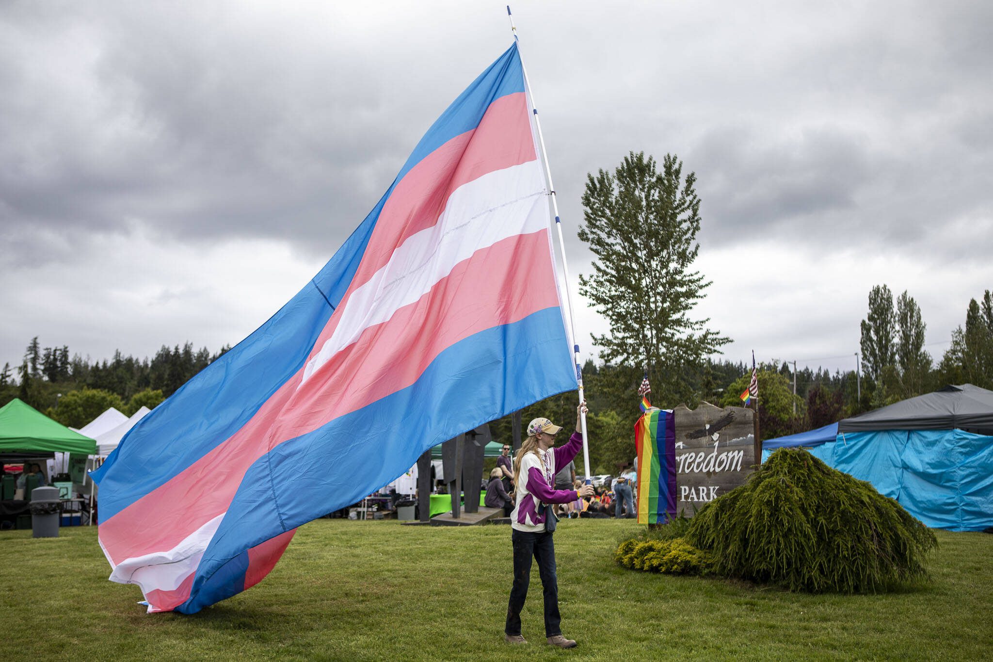Sam Schrantz waves a transgender pride flag during the Stanwood-Camano Pride event at Freedom Park in Camano, Washington on Saturday, June 1, 2024. (Annie Barker / The Herald)