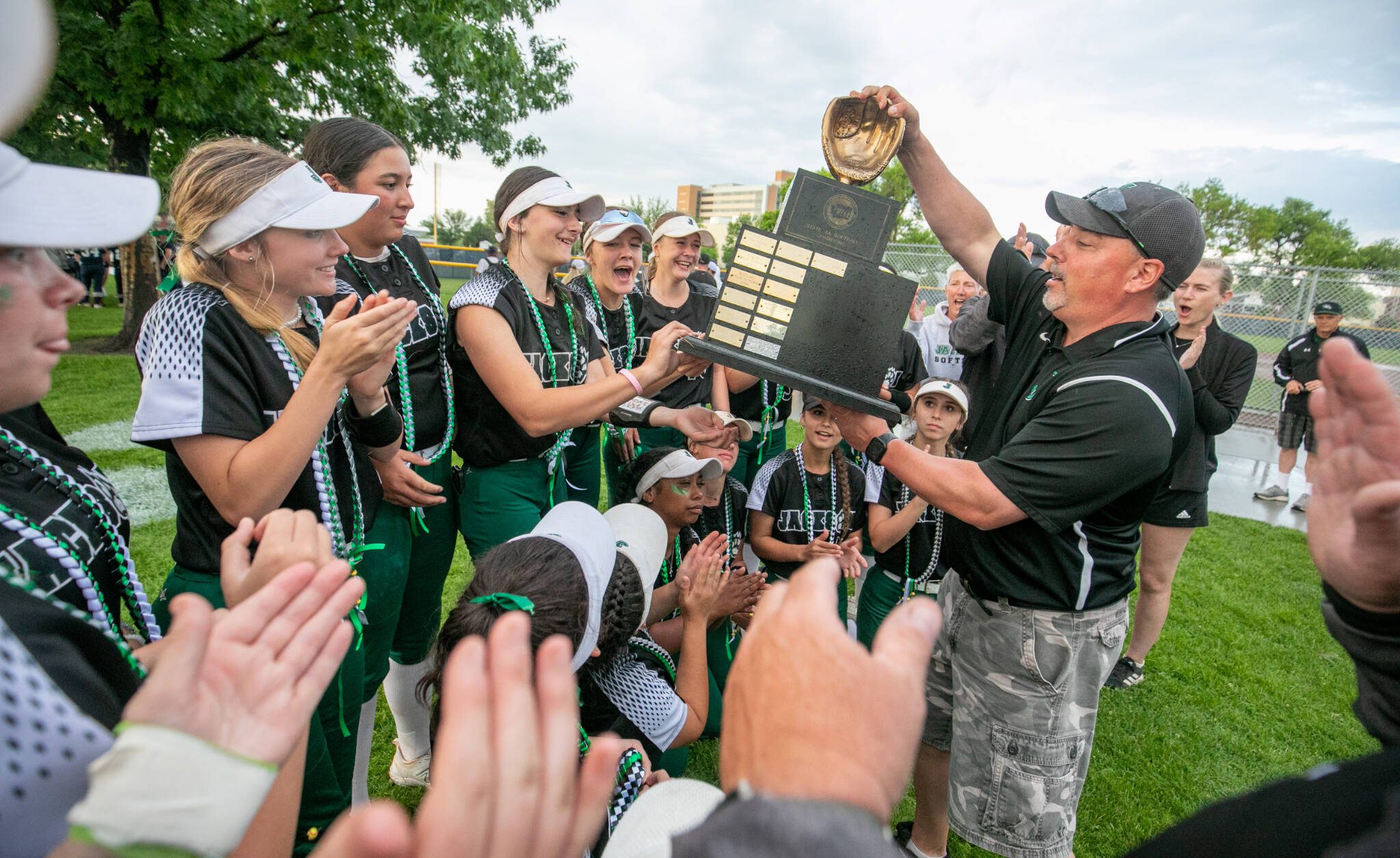 Jackson High School softball coach Kyle Peacocke hands the 2023 Class 4A softball championship trophy to the team after their win last year in Richland. Peacocke is stepping down after 13 years coaching the Timberwolves. (TJ Mullinax / for The Herald)