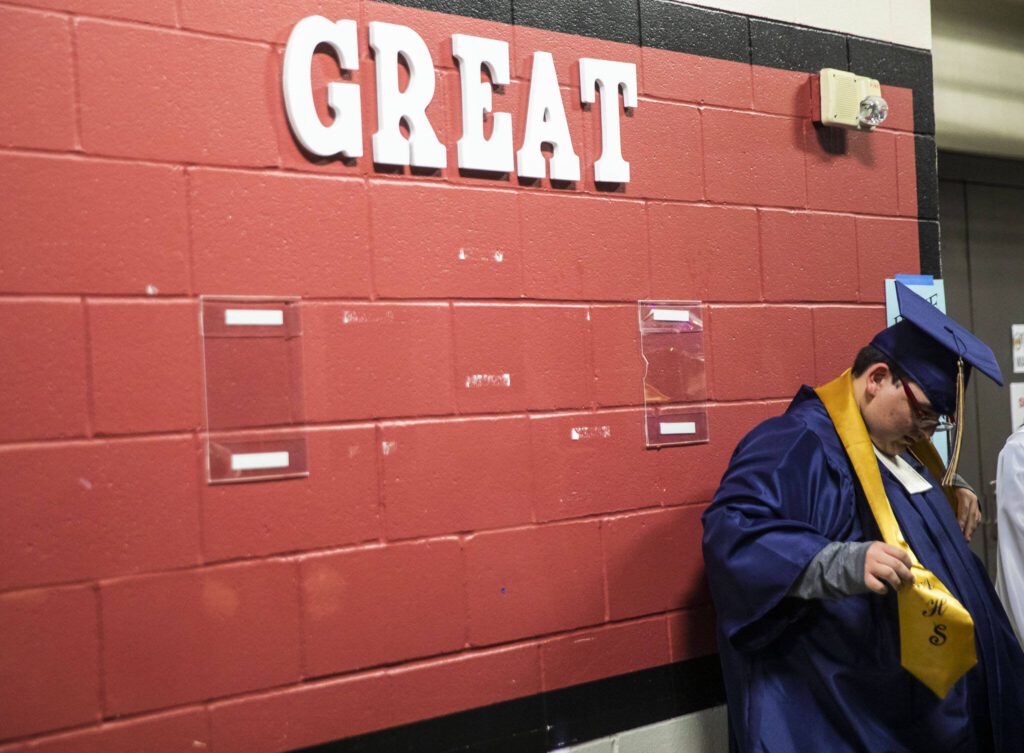 A student adjusts their robe during Arlington High School graduation at Angel of the Winds Arena on Thursday, June 13, 2024, in Everett, Washington. (Olivia Vanni / The Herald)
