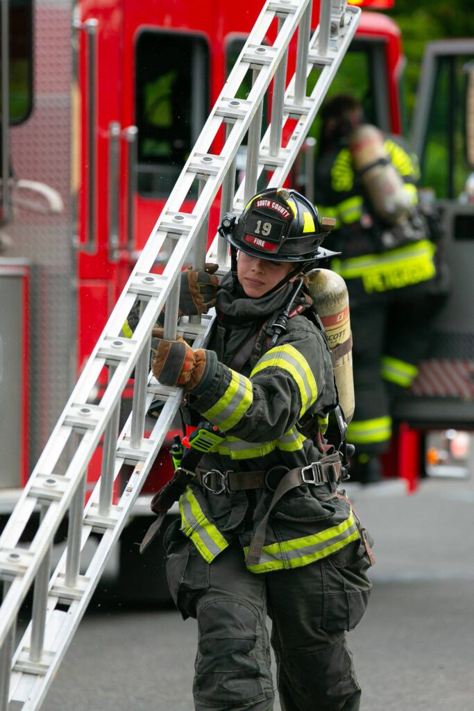A South County firefighter carries a ladder during a simulated firefighting demonstration during the Future Women in EMS/Fire Workshop on Saturday, June 22, 2024, at the South County Fire Training Center in Everett, Washington. (Ryan Berry / The Herald)
