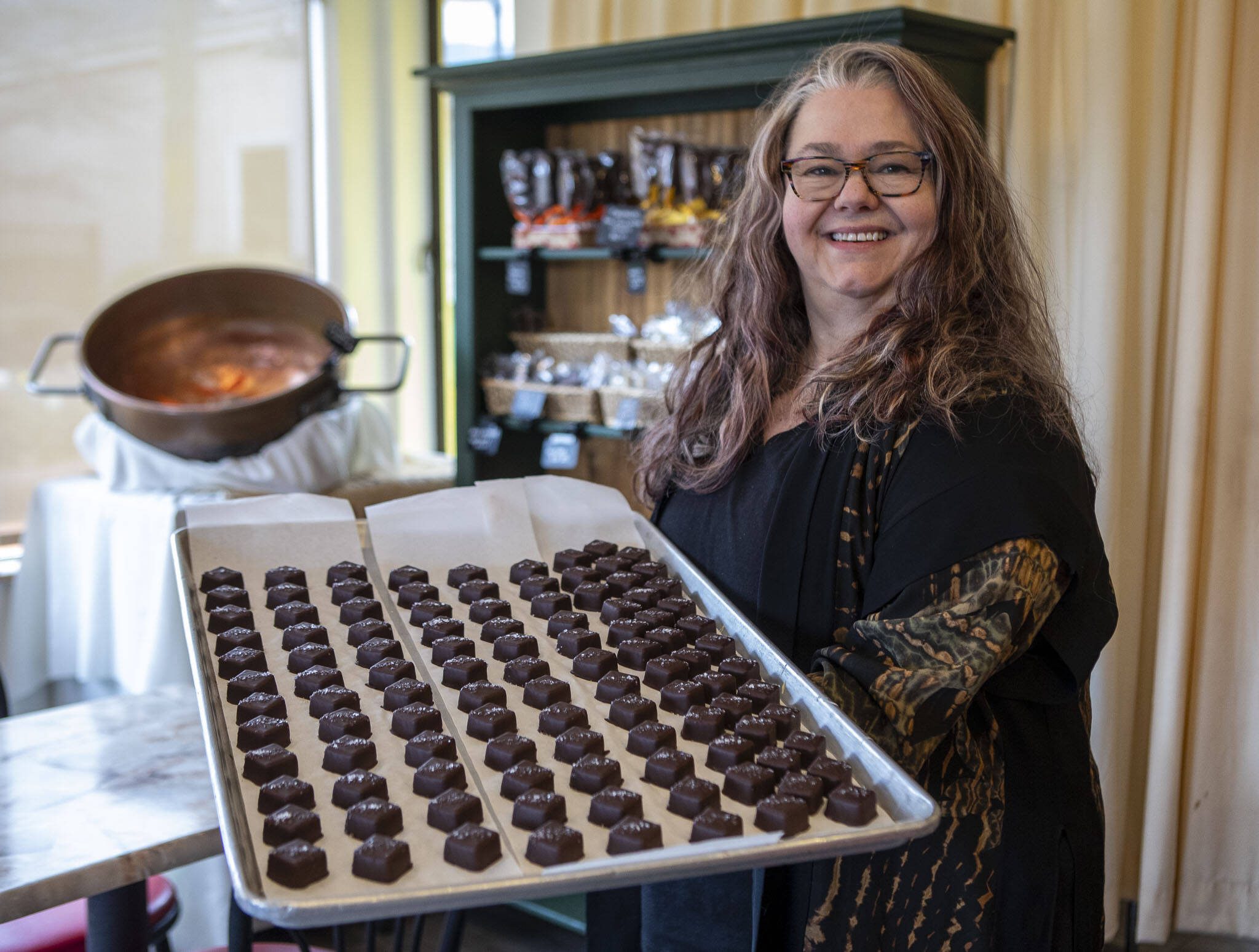 Mona Newbauer poses for a photo with caramels inside her store Sweet Mona’s Chocolates on March 21, 2024 in Langley. (Annie Barker / The Herald)