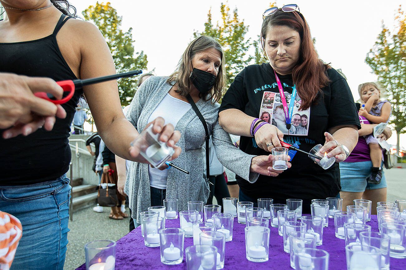 Christina Cratty, right, and her mother Storm Diamond, left, light a candle for their family member Monique (Mo) Wier who died from an overdose last July during A Night to Remember, A Time to Act opioid awareness event at the Snohomish County Campus on Thursday, Aug. 29, 2024 in Everett, Washington. (Olivia Vanni / The Herald)