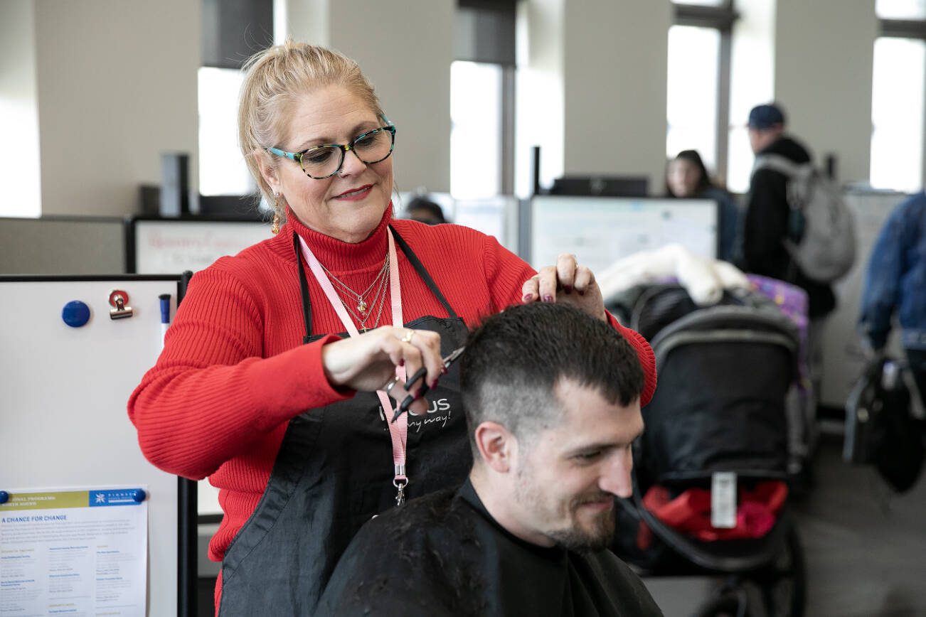 Bethany Teed, a certified peer counselor with Sunrise Services and experienced hairstylist, cuts the hair of Eli LeFevre during a resource fair at the Carnegie Resource Center on Wednesday, March 6, 2024, in downtown Everett, Washington. (Ryan Berry / The Herald)