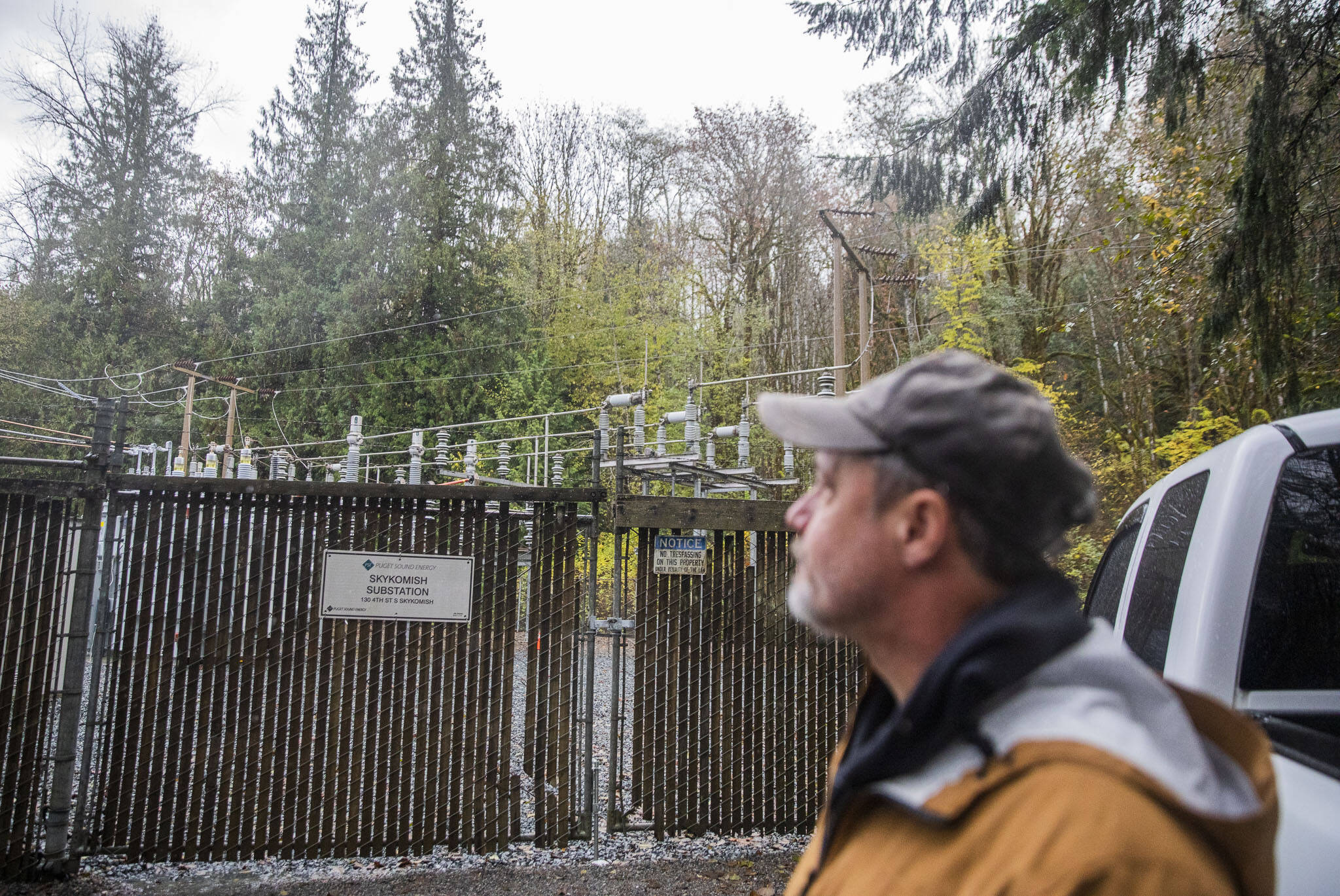 Vernon Streeter looks over the fence at the Skykomish Substation operated by Puget Sound Energy on Monday, Nov. 4, 2024 in Skykomish, Washington. (Olivia Vanni / The Herald)