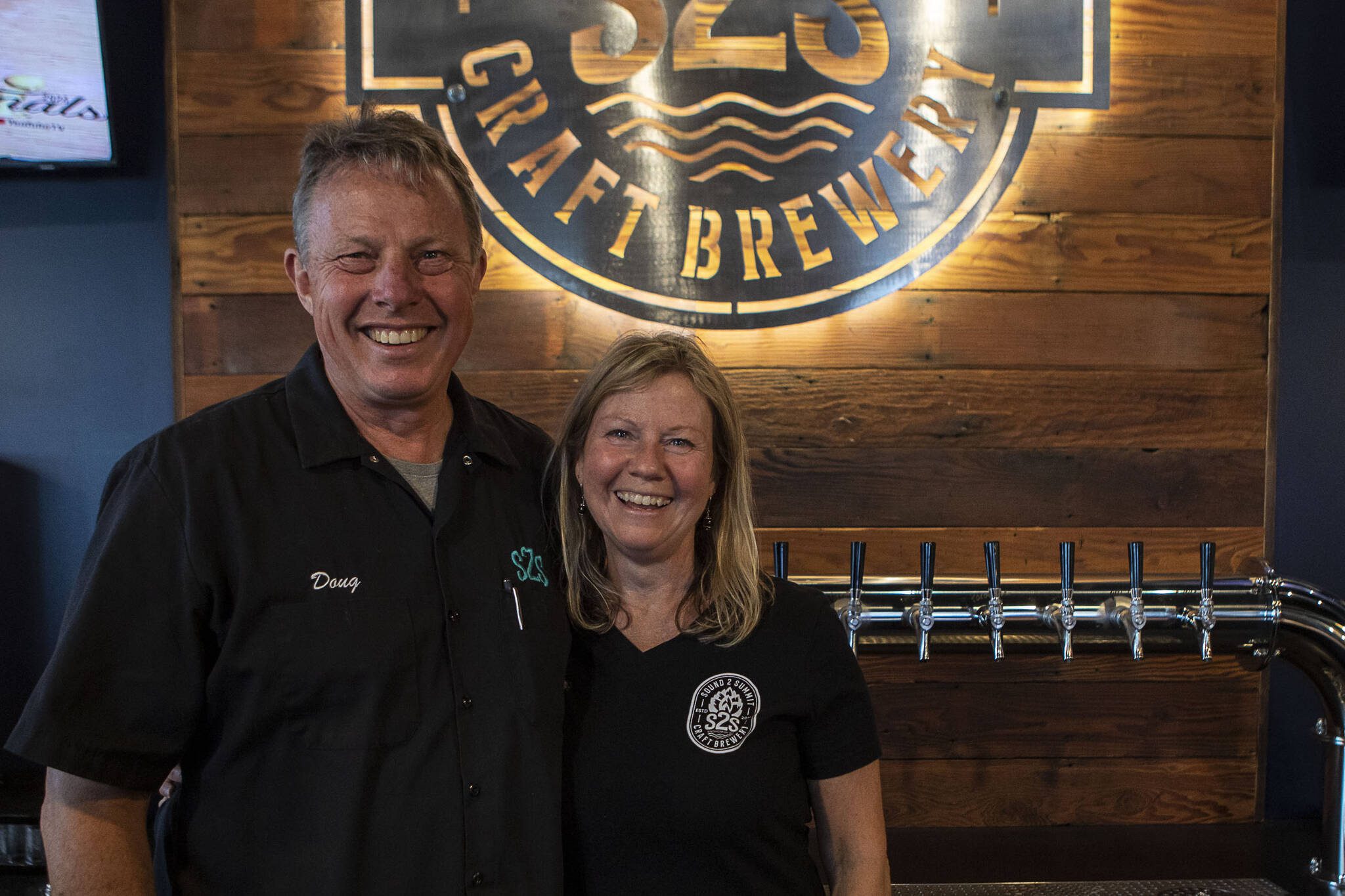 Owners Doug Milnor, left, and Christine Milnor, right, pose for a photo inside the new Sound To Summit Brewing location in Everett, Washington. (Annie Barker / The Herald)