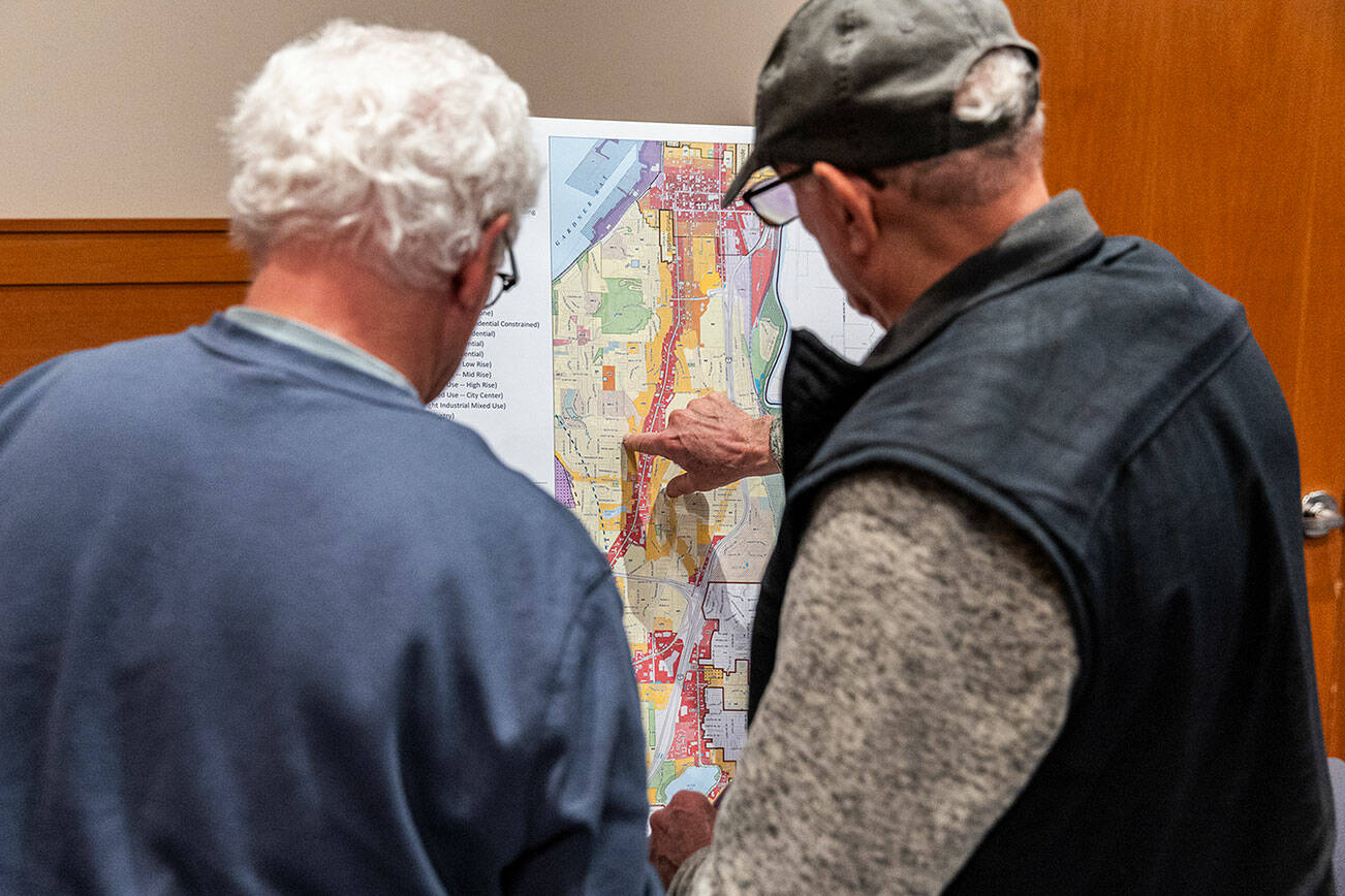 Pat Cronin and Jamie Lyon look over a zoning district map draft of Everett on display during an Everett Planning Department open house at Everett Station on Wednesday, Feb. 26, 2025 in Everett, Washington. (Olivia Vanni / The Herald)