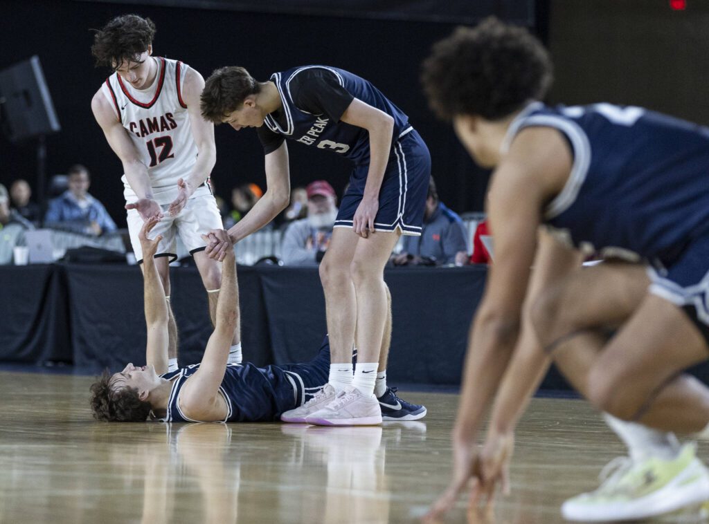 Glacier Peak’s Jo Lee is helped up by his teammate Jack Taylor and Camas’ Jace VanVoorhis after the final buzzer sending the game into overtime during the 4A boys quarterfinal game against Camas on Thursday, March 6, 2025 in Tacoma, Washington. (Olivia Vanni / The Herald)
